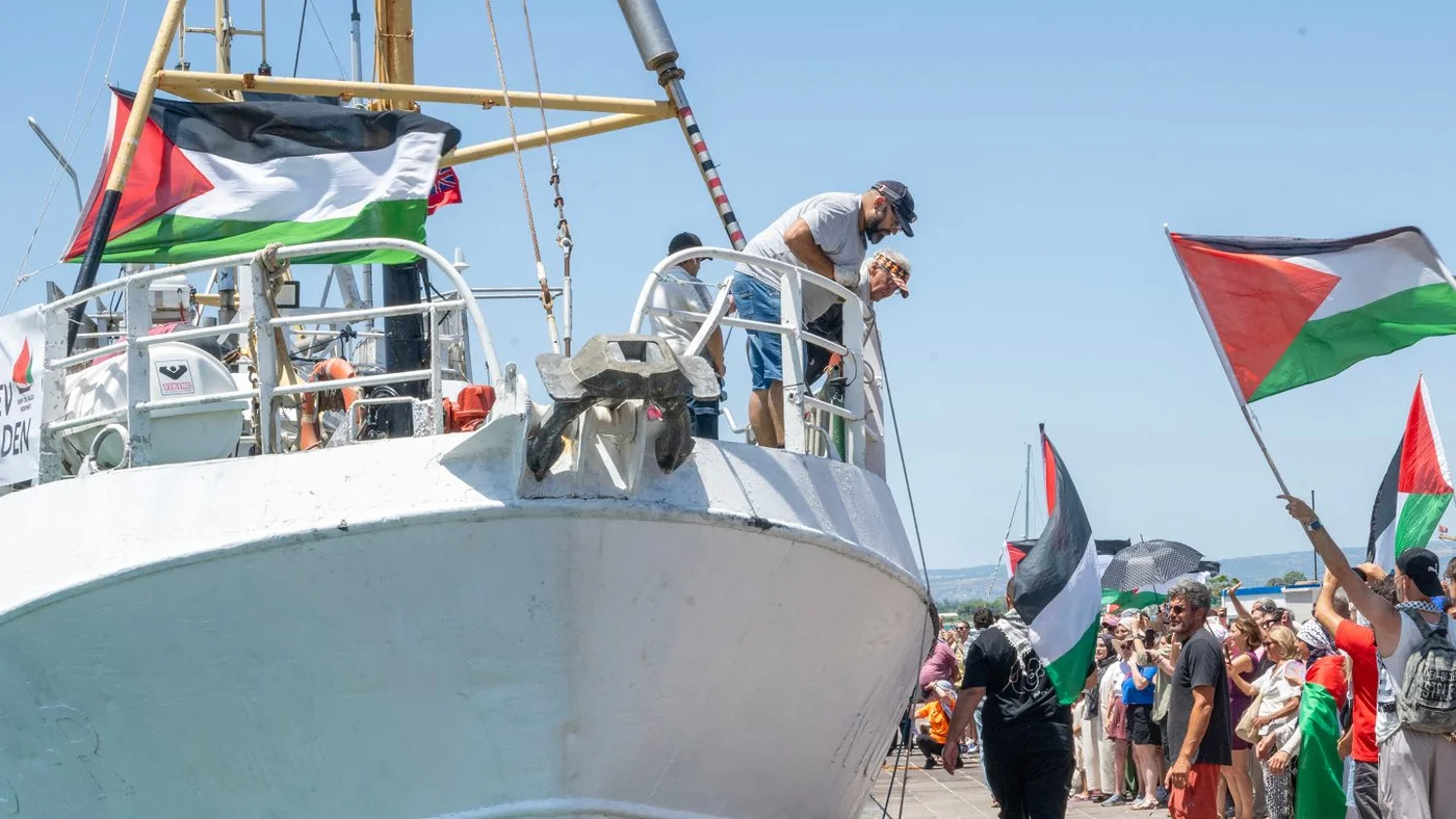 Demonstrators with Palestinian flags gather beside the Freedom Flotilla ship Handala before its departure for Gaza from Sicily, Italy, 13 July 2025 (Giovanni Isolino/AFP)